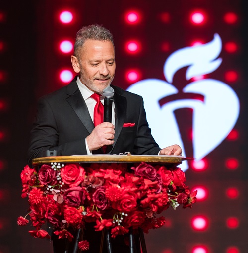 Man in tux speaking into microphone at the podium.